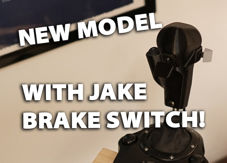 May include: A black 3D-printed device with a rounded top and a Jake Brake Switch. The text "NEW MODEL" and "WITH JAKE BRAKE SWITCH!" are displayed in white, bold font.