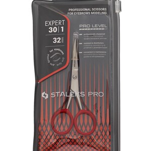 Könnte beinhalten: Professionelle Augenbrauenschere in einer transparenten Kunststoffverpackung. Die Schere hat rote Griffe und silberne Klingen. Die Verpackung enthält den Text "EXPERT 30|1 32 mm für Augenbrauen" und "STALEKS PRO".