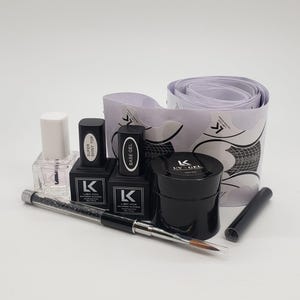 Puede incluir: Un kit de arte de uñas con varios frascos y recipientes en blanco y negro de productos para uñas, incluyendo gel base, gel UV y capa superior. También se incluyen un pincel de uñas y formas de uñas. La marca "K" y "LIBA KON" son visibles.
