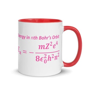 May include: A white ceramic mug with a bright red interior and handle. The exterior features pink text that reads Energy in nth Bohr's Orbit followed by the physics equation En = - (mZ^2e^4) / (8ε0^2h^2n^2) printed in a clear, bold font.
