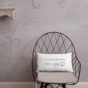 May include: A rectangular white throw pillow featuring the black printed text Frequentist Probability and the mathematical formula P(I) = lim N→∞ (n/N) centered on the front surface. The pillow has a smooth fabric finish and clean edges.