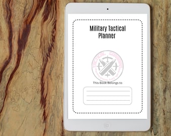 Può includere: Un tablet bianco mostra la copertina di un "Military Tactical Planner". La copertina include un logo con proiettili incrociati e il testo "This Book Belongs to" con linee per il nome del proprietario. Il tablet è su una superficie di legno.