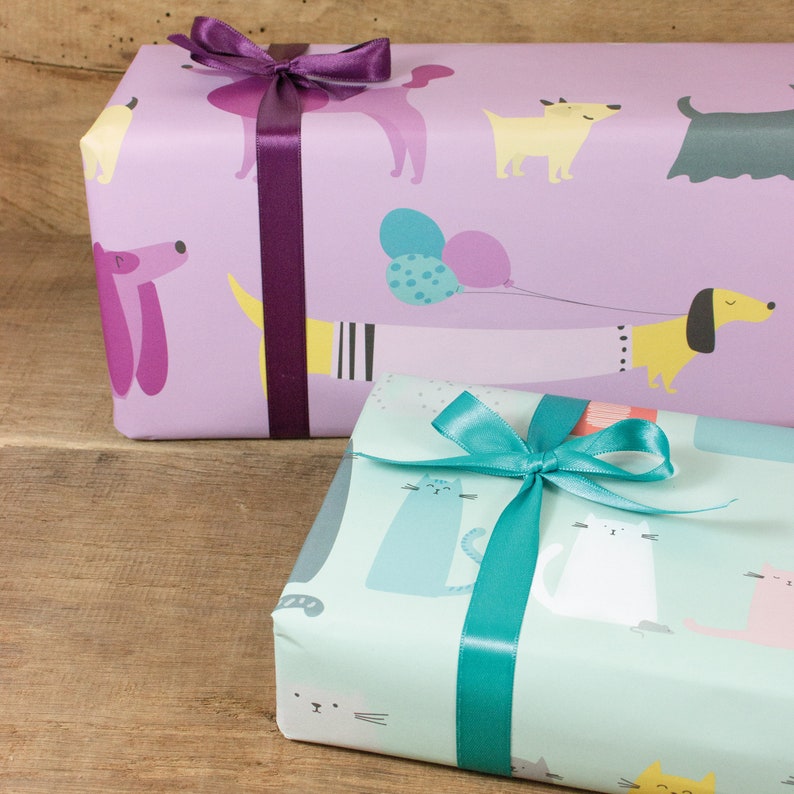 May include: Two wrapped gifts, one with a purple ribbon and a purple and yellow dog pattern, the other with a teal ribbon and a blue and white cat pattern.