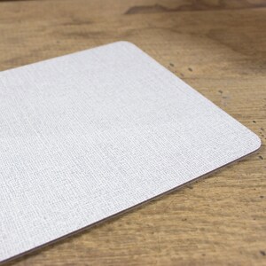May include: A white placemat with a subtle textured surface. The placemat has a slightly rounded edge.