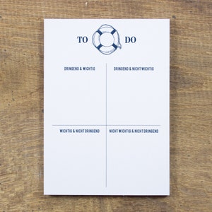 Könnte beinhalten: Eine weiße To-Do-Liste mit einer blauen Rettungsring-Grafik in der oberen Mitte. Die Liste ist in vier Quadranten unterteilt mit folgenden Überschriften: Dringend & Wichtig, Dringend & Nicht Wichtig, Wichtig & Nicht Dringend, Nicht Wichtig & Nicht Dringend.