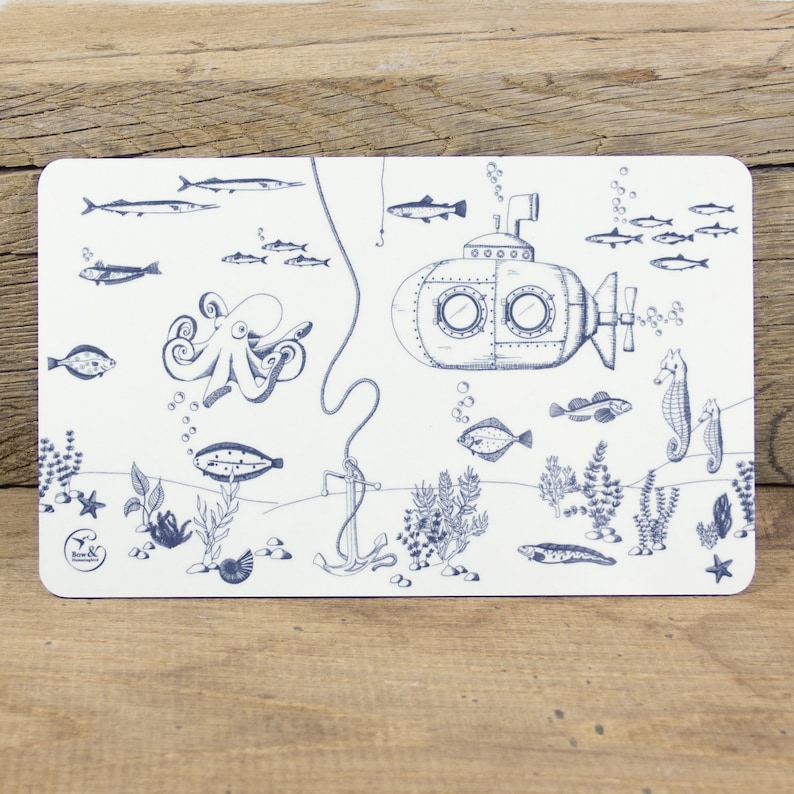 May include: A white placemat with a blue and white illustration of a submarine, an octopus, fish, and seaweed. The placemat has the text "Bow & Co." in the bottom left corner.