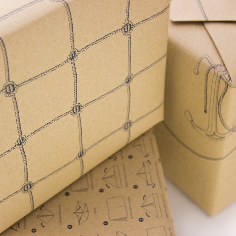 Puede incluir: Dos rollos de papel de regalo marr&oacute;n con dise&ntilde;os n&aacute;uticos. Un rollo presenta un patr&oacute;n de red de cuerda, el otro tiene un dise&ntilde;o de ancla.