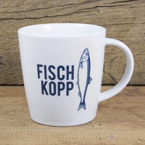 Könnte beinhalten: Weiße Keramiktasse mit einer blauen Fischillustration und dem Text "FISCH KOPP" in blau.