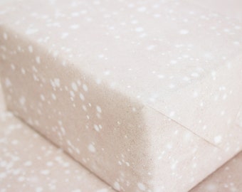 Könnte beinhalten: Nahaufnahme von hellbraunem Geschenkpapier mit einem weißen, gepunkteten Muster. Das Papier hat eine subtile Textur und eine weiche, gedämpfte Farbe.