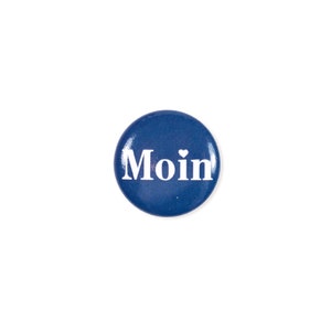 Pode incluir: Um bot&atilde;o redondo azul com a palavra "Moin" em letras brancas e um pequeno cora&ccedil;&atilde;o branco sobre o "i".