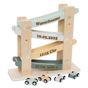Könnte beinhalten: Eine hölzerne Spielzeugrennstrecke mit drei Ebenen und einem hellblauen, grauen und gelben Farbschema. Die Strecke hat eine personalisierte Inschrift mit einem Namen, Datum und Uhrzeit. Die Inschrift lautet "Wunschname", "10.02.2025" und "11:15 Uhr". Die Strecke enthält auch die Maße "52 cm 3450 g". Die Strecke wird mit sechs kleinen Spielzeugautos geliefert.