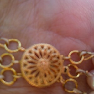 Peut inclure: Un collier en cha&icirc;ne dor&eacute;e avec un fermoir d&eacute;coratif et plusieurs rangs de perles.