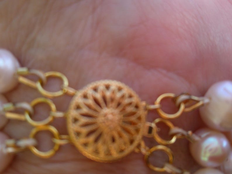 Peut inclure: Un collier en cha&icirc;ne dor&eacute;e avec un fermoir d&eacute;coratif et plusieurs rangs de perles.