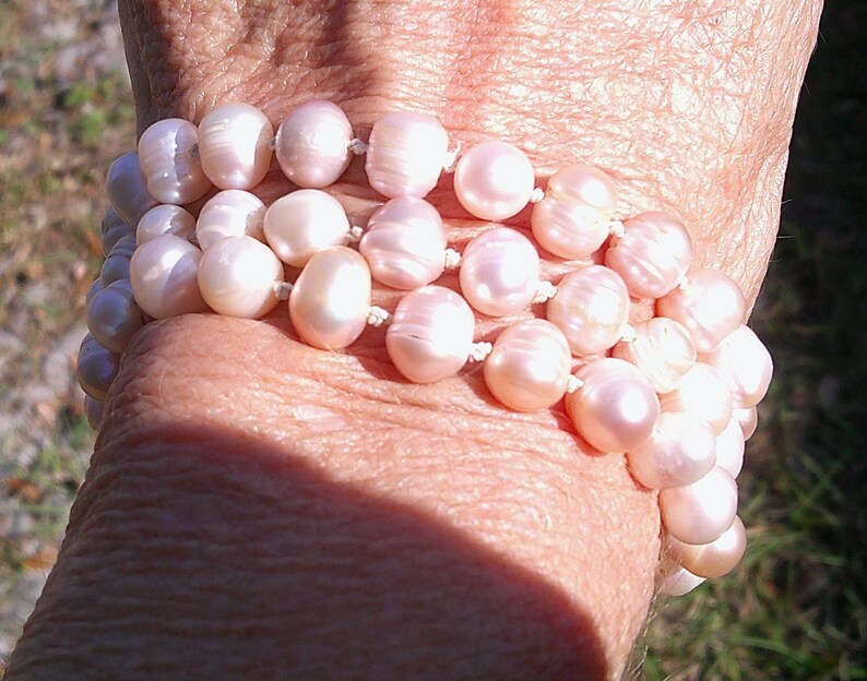 Peut inclure: Un bracelet compos&eacute; de plusieurs rangs de perles roses. Les perles sont rondes et lisses, et elles sont enfil&eacute;es sur un cordon blanc.