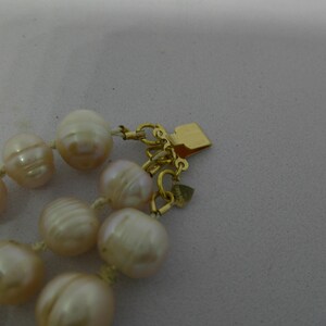 Peut inclure: Un collier de perles de couleur cr&egrave;me avec un fermoir en or. Les perles sont rondes et ont un l&eacute;ger &eacute;clat iridescent.