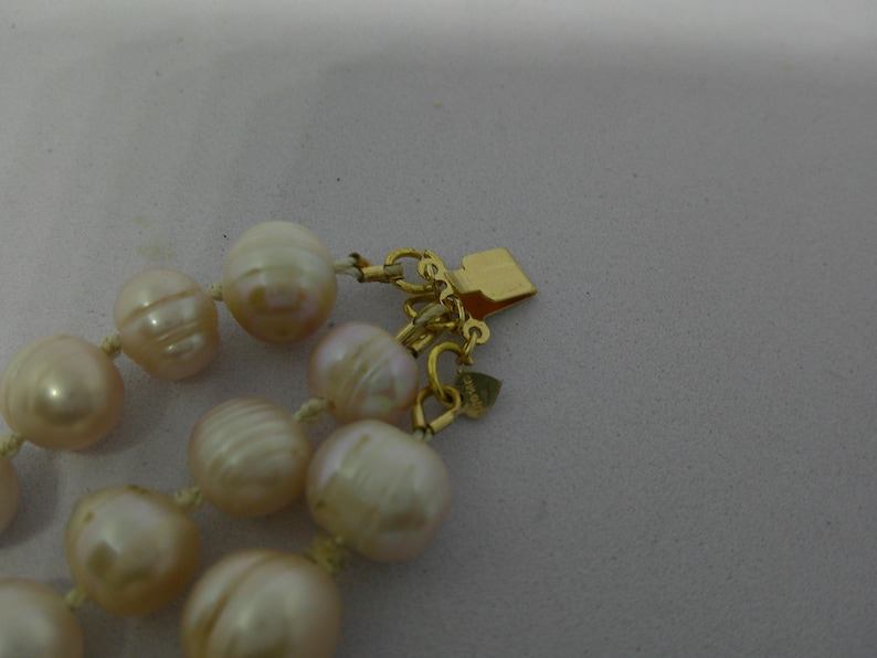 Peut inclure: Un collier de perles de couleur cr&egrave;me avec un fermoir en or. Les perles sont rondes et ont un l&eacute;ger &eacute;clat iridescent.