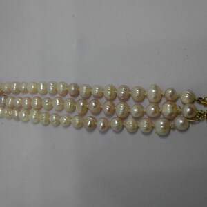 Peut inclure: Un collier de perles &agrave; trois rangs avec un fermoir en or. Les perles sont blanches et ont une l&eacute;g&egrave;re teinte rose.