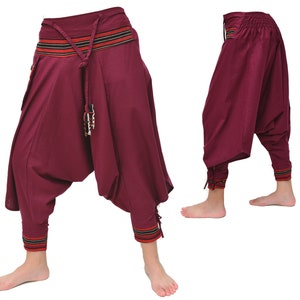 May include: Burgundy-colored pants with a wide, gathered leg and a decorative waistband with black and orange stripes. The pants have a drawstring closure and a tassel.
