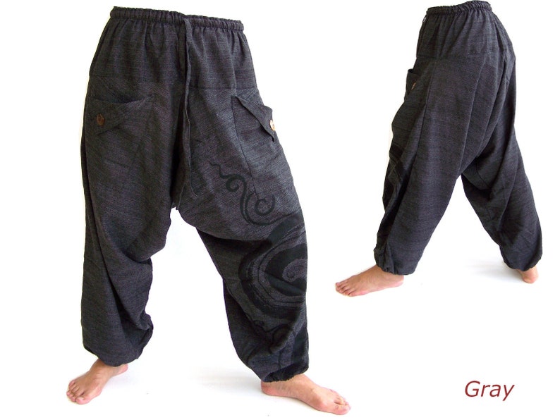 May include: Gray, loose-fitting pants with a drawstring waist and a decorative design on the leg. The pants have two large pockets on the front.