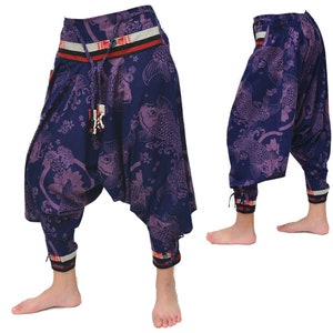 Puede incluir: Pantalones de patrón morado y azul con una cintura roja y blanca. Los pantalones tienen un corte holgado y fluido y están hechos de una tela ligera.