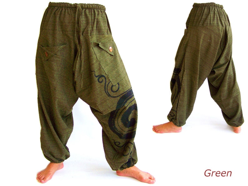 May include: Green, loose-fitting pants with a drawstring waist and a black design on the leg. The pants have pockets on the sides.
