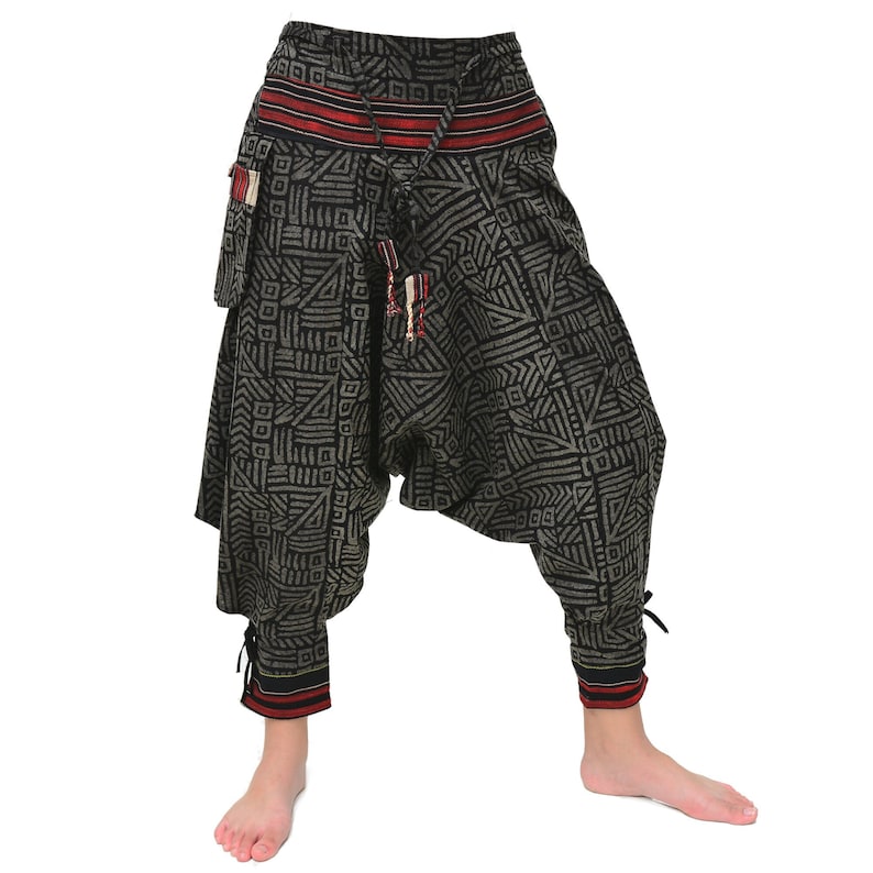 May include: Black and gray patterned pants with a red and black waistband. The pants have a drawstring and a decorative tassel. The pants are loose fitting and have a wide leg.