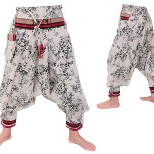 May include: White pants with a black floral print and red and black trim. The pants have a drawstring waist and a wide leg.