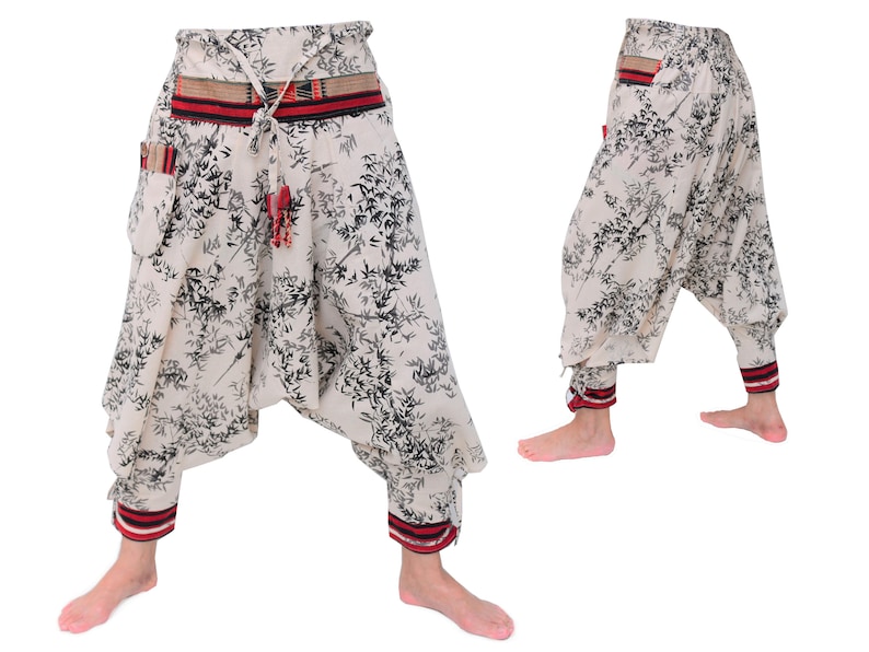 May include: White pants with a black floral print and red and black trim. The pants have a drawstring waist and a wide leg.