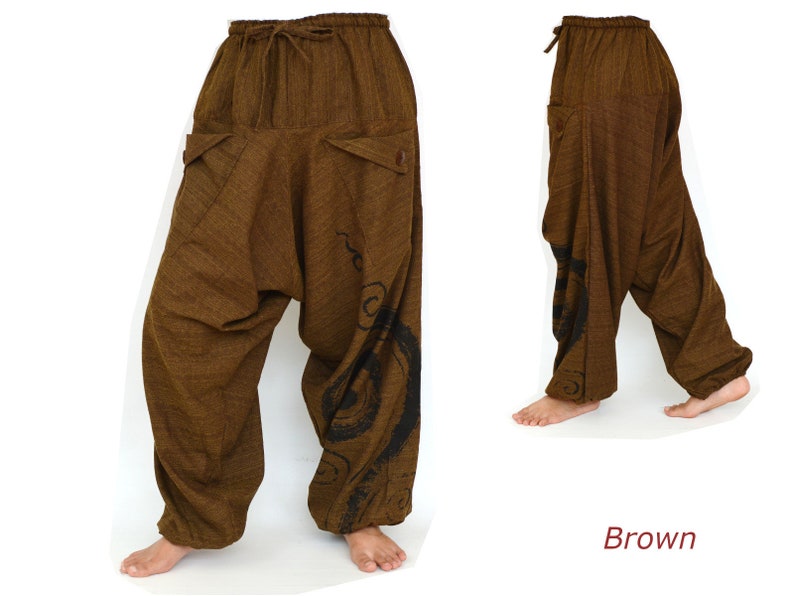 May include: Brown, loose-fitting pants with a drawstring waist and a black swirl design on the right leg. The pants are made of a soft, comfortable fabric.