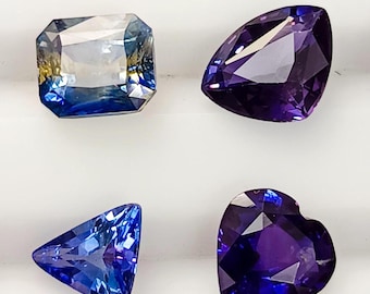 May include: Four faceted gemstones arranged in a grid. Top left is a rectangular blue and yellow stone. Top right is a pear-shaped deep purple stone. Bottom left is a triangular bright blue stone. Bottom right is a heart-shaped dark purple stone.