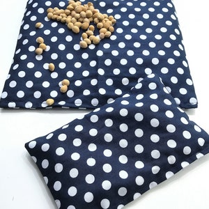 May include: Two blue fabric pouches with white polka dots. The larger pouch is lying flat and the smaller pouch is folded in half. Both pouches are filled with small, beige beans.