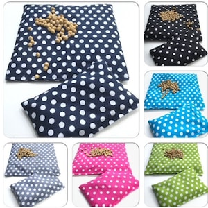 May include: Set of six polka dot heat packs in various colors, including navy blue, black, turquoise, pink, gray, and green. Each pack has a smaller matching pack inside. The larger packs are filled with beans and can be heated in the microwave.