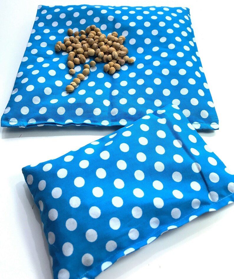 May include: Two blue and white polka dot fabric pouches. The larger pouch is lying flat and the smaller pouch is folded in half. Both pouches are made of a soft, cotton fabric.