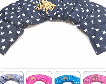 May include: A set of four blue, pink, gray, and white star patterned neck pillows. Each pillow is filled with buckwheat hulls and is shaped like a crescent moon. The pillows are arranged in a row, with the blue pillow in the center.