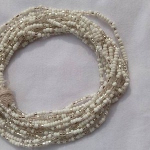 Op de afbeelding: Een witte kralenketting voor de taille met een witte strik. De kralen zijn klein en rond, en de ketting is ongeveer 76 cm lang.