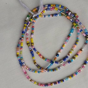 Op de afbeelding: Veelkleurige kralen tailleketting met een verscheidenheid aan kleuren, waaronder blauw, geel, roze, wit en goud.