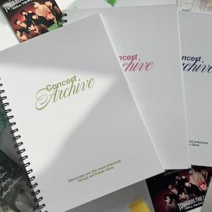 Könnte beinhalten: Weiße Notizbücher mit dem Schriftzug "Concert Archive" in Grün, Rosa und Blau. Enthält ein Spiralbuch, ein Schlüsselband und Karten mit den Texten "Towards the Light" und "Memories are the most precious things we'll ever have."
