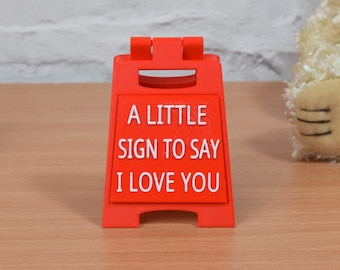 May include: A red plastic sign with the text "A little sign to say I love you".