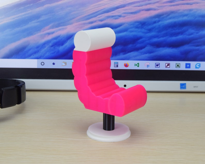 May include: A pink and white miniature armchair with a rounded, fluted back and a white top. The chair is on a white base.