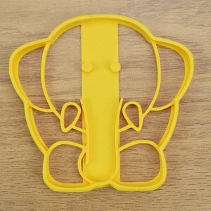 May include: Yellow plastic cookie cutter shaped like an elephant with a raised trunk and ears.