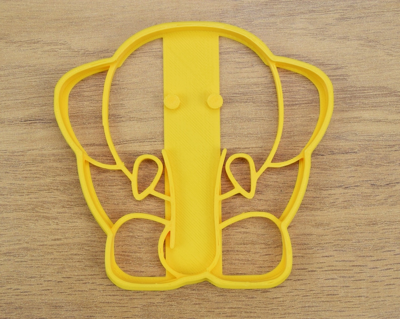 May include: Yellow plastic cookie cutter shaped like an elephant with a raised trunk and ears.