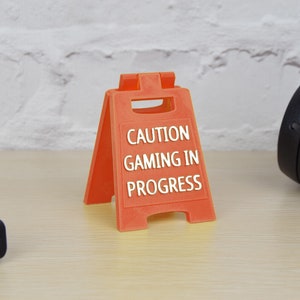May include: Orange plastic caution sign with the text "CAUTION GAMING IN PROGRESS".