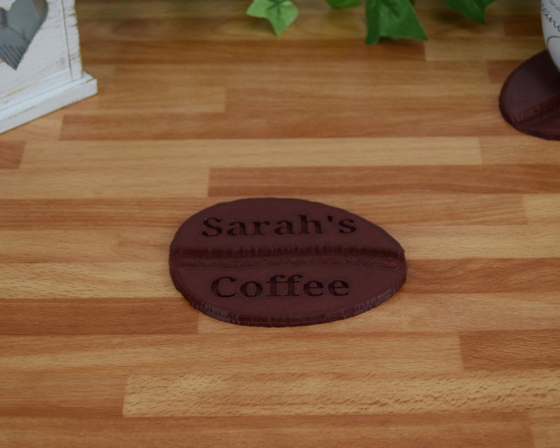 May include: A brown coffee cup coaster with the text "Sarah's Coffee" engraved on it.