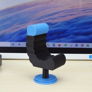 May include: A black and blue miniature chair with a rounded backrest and a circular base. The chair is made of a smooth, plastic-like material.