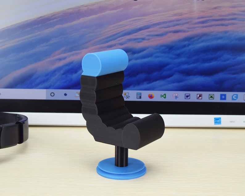 May include: A black and blue miniature chair with a rounded backrest and a circular base. The chair is made of a smooth, plastic-like material.