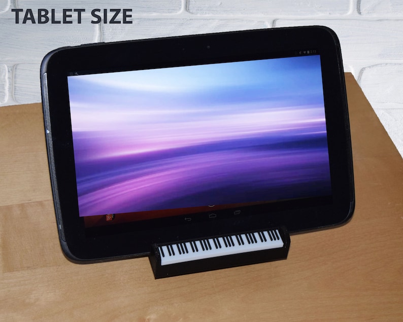 Puede incluir: Una tableta negra con un fondo degradado morado y azul en la pantalla. La tableta est&aacute; sobre un soporte de teclado negro.