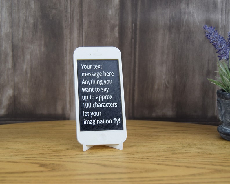 May include: White phone stand with a black screen displaying the text "Your text message here Anything you want to say up to approx 100 characters let your imagination fly!"