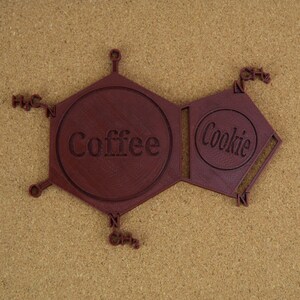 Puede incluir: Un modelo 3D impreso en marr&oacute;n de una estructura qu&iacute;mica con las palabras "Coffee" y "Cookie" en el centro de cada anillo.