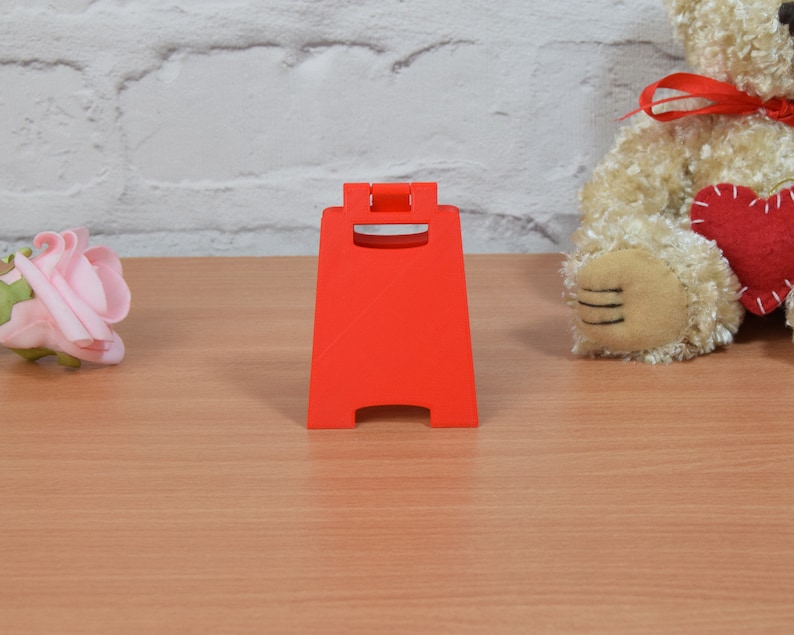 Op de afbeelding: Een felrood, plastic A-frame bord met afgeronde hoeken en een vlak oppervlak. Het bord staat op een houten tafel.