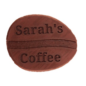 May include: A brown ceramic coffee bean with the text "Sarah's Coffee" embossed on the surface.